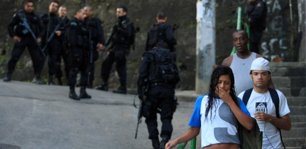 Pessoas passam por policiais durante ocupação da comunidade do Cerro Corá, no Cosme Velho, zona sul do Rio - Fábio Teixeira/Agência O Globo