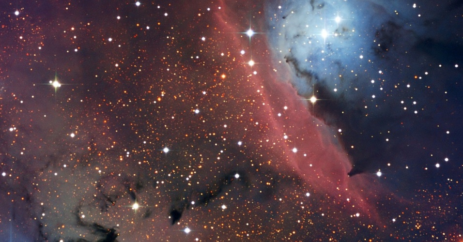 2.mai.2013 - Telescópio dinamarquês do Observatório La Silla, no Chile, fez novas imagens da nebulosa NGC 6559, que fica a 5.000 anos-luz de distância da Terra, na constelação de Sagitário. Essa nuvem de gás e poeira é um pequeno berçário de estrelas, com poucos anos-luz de dimensão. Segundo o Observatório Europeu do Sul (ESO, na sigla em inglês), a radiação emitida pelas estrelas recém-nascidas é reenviada pelo hidrogênio gasoso da nuvem, criando essa região vermelha no centro da imagem. Já a mancha azulada, que está próxima da nebulosa de emissão vermelha, indica a radiação emitida pelas novas estrelas que é dispersada em várias direções pelas partículas microscópicas e sólidas que existem na NGC 6559 - poeira compostas por elementos pesados, como carbono, ferro ou silício