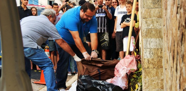 Peritos da polícia examinam o corpo encontrado dentro de uma mala - Nivaldo Lima/Futura Press