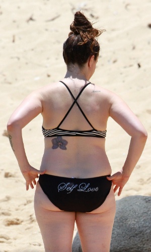 4.mai.2013 - Alanis Morissette curtiu praia com o filho, Ever, no Havaí. A cantora vestiu biquíni com a frase "self love" ("amor próprio"