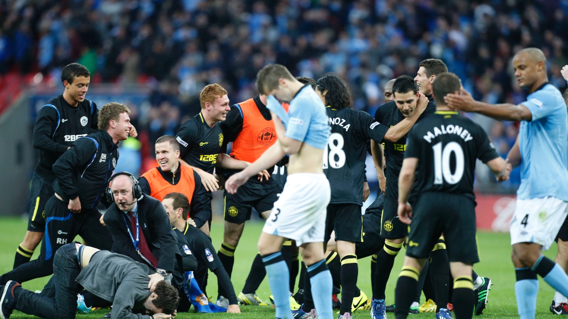 Jogadores do Wigan comemoram título da Copa da Inglaterra, para decepção dos jogadores do Manchester City - Jon Super / AP