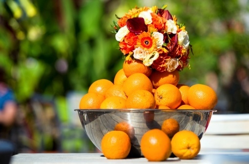 A combinação flores e frutas é outra campeã em casamentos. Neste centro de mesa, o recipiente de metal recebeu laranjas e um arranjo de flores - Thinkstock