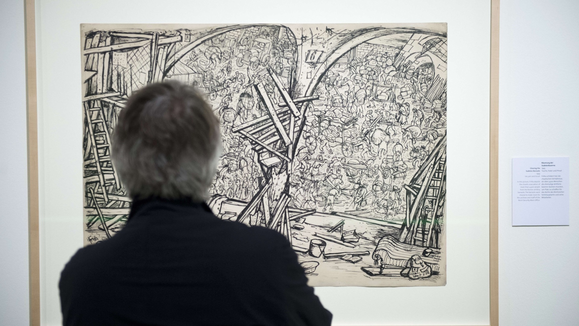 15.mai.2013 - Desenho "Clearing the Sudeten Barracks" é observado por visitante da mostra "Bedrich Fritta: desenhos do gueto de Theresienstadt", que reúne obras feitas clandestinamente pelo artista Bedrich Fritta enquanto viveu em campo de concentração - John MacDougall/AFP