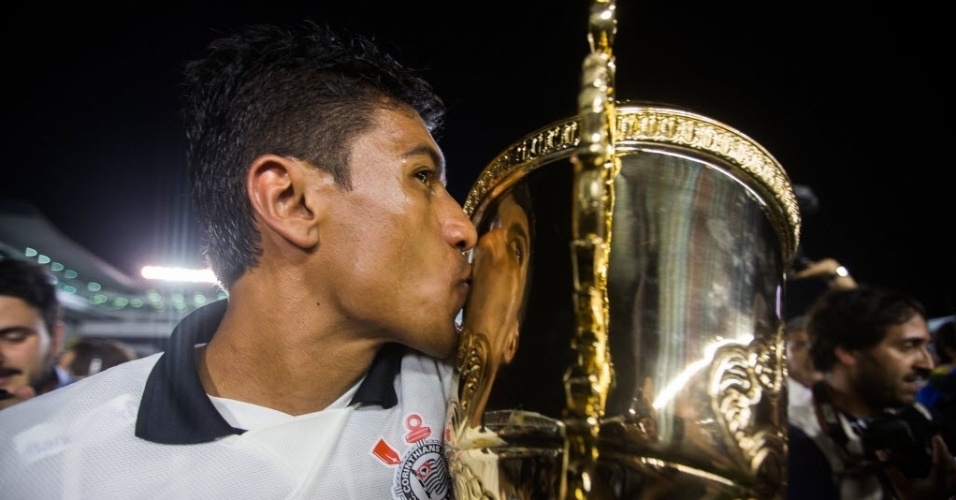 19.mai.2013 - Paulinho, volante do Corinthians, beija a taça de campeão paulista ainda no gramado da Vila Belmiro