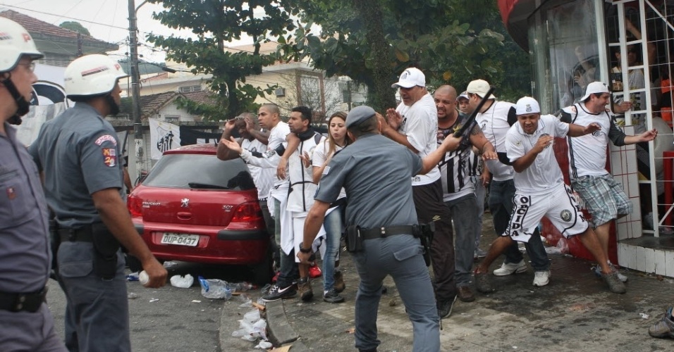 19.mai.2013 - Policial usa o cacetete para acertar torcedores do Santos durante confronto antes da decisão do Paulista