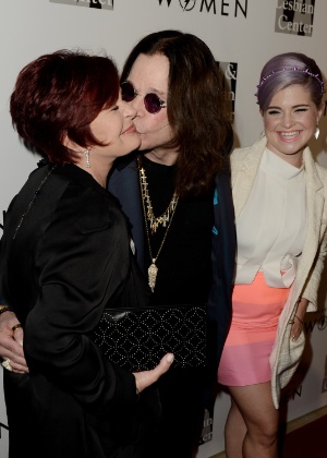 Sharon Osbourne e Ozzy Osbourne se beijam enquanto a filha, Kelly, os observa em maio de 2013  - Kevin Winter/Getty Images