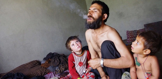 Abdul Rahman, 44, fuma ópio enquanto é observado por seus filhos, em Laghman, no Afeganistão - Waseem Nikzad/AFP