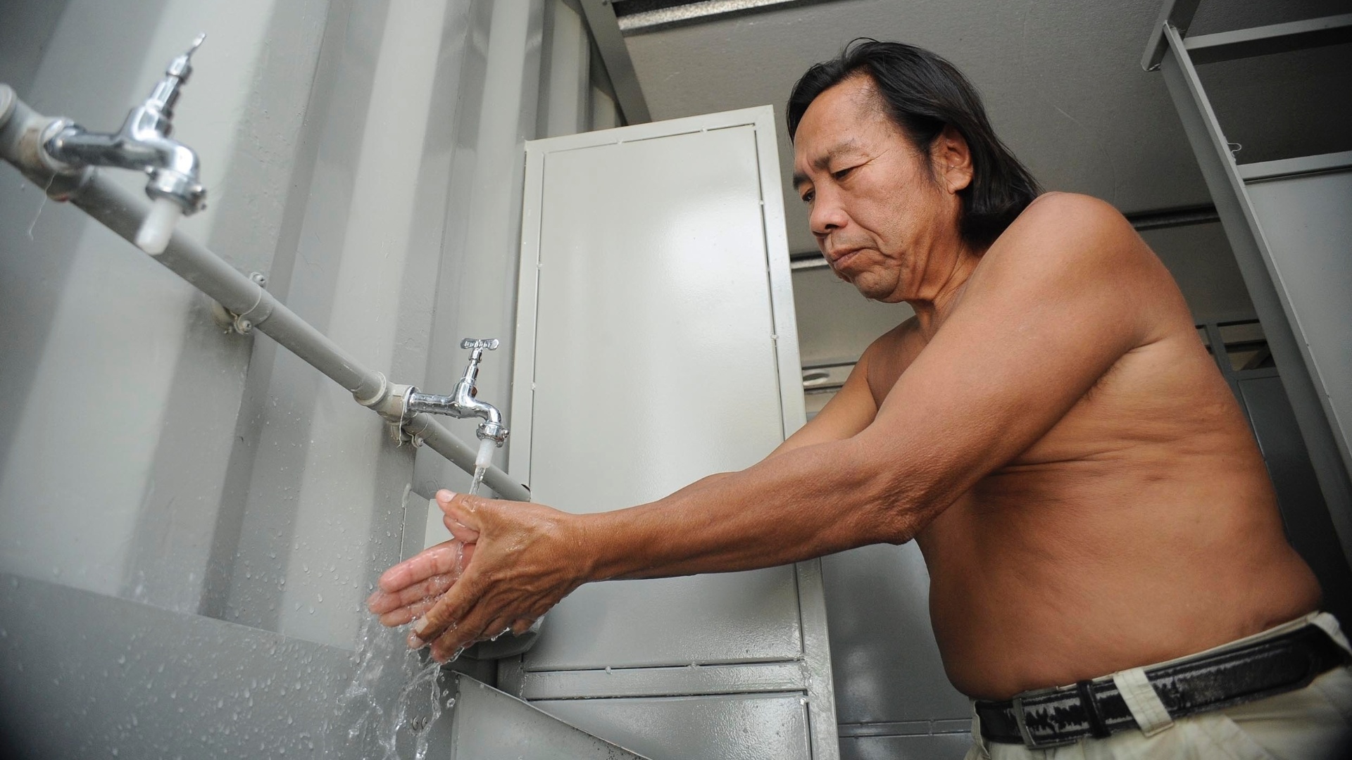 22.mai.2013 - Cacique Doethyró, da etnia Tukano, lava as mãos em torneira improvisada na Colônia Curupaiti, em Jacarepaguá, na zona oeste do Rio de Janeiro. As famílias indígenas que antes viviam na Aldeia Maracanã, na zona norte da capital fluminense, foram viver no local em contêineres e sem água potável - Fabio Teixeira/UOL