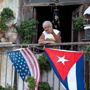 Cubano acena de varanda decorada com bandeiras dos EUA e de Cuba, em Havana, em foto de janeiro de 2015 - Yamil Lage/ AFP
