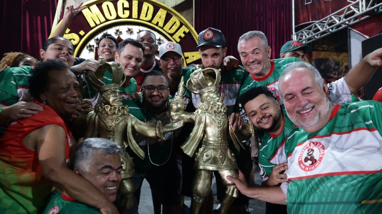 Integrantes da Mocidade Alegre com troféu de campeã na quadra da escola  