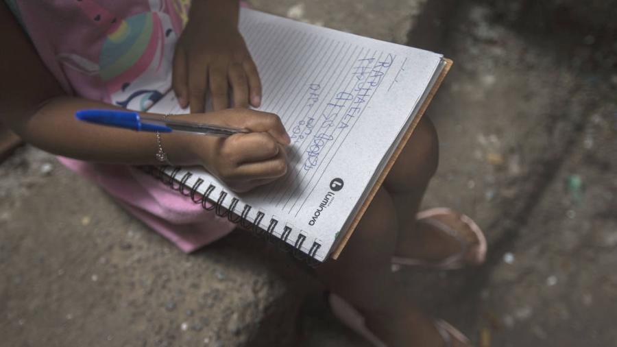 Menina de 5 anos, aluna de escola municipal de São Paulo, tenta escrever o próprio nome; educação foi um dos desafios que crianças e adolescentes vivenciaram durante a pandemia de Covid-19