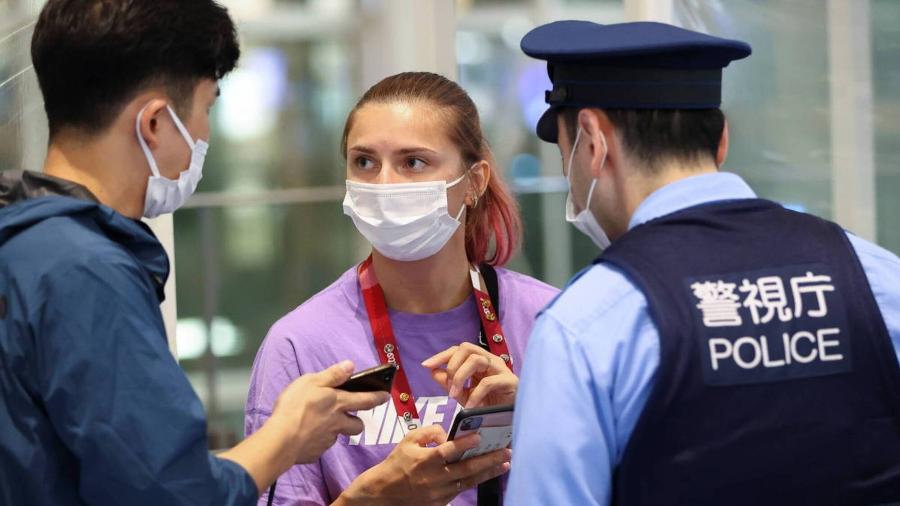 A atleta bielorrussa Krystsina Tsimanouskaya conversa com um policial no Aeroporto Internacional de Tóquio - Issei Kato/Reuters