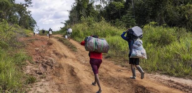 Garimpeiros caminham em estrada de terra no meio da floresta