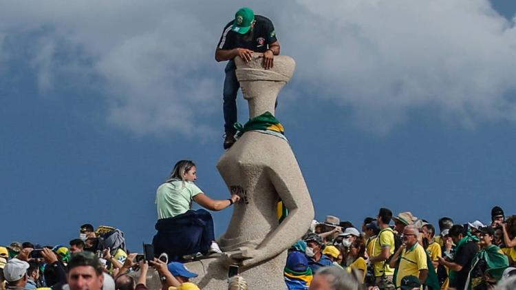 Mulher picha 'Perdeu, mané', na estátua 'A Justiça', durante invasão às sedes dos Três Poderes