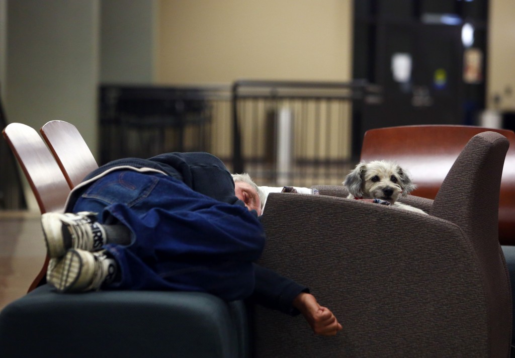 A man and his dog sleep on a makeshift bed at a recreational centre in Lac la Biche, Alberta on May 5, 2016 after fleeing forest fires north of Fort McMurray. Raging wildfires pressed in on the Canadian oil city of Fort McMurray Thursday after more than 80,000 people were forced to flee, abandoning fire-gutted neighborhoods in a chaotic evacuation. No casualties have been reported from the monster blaze, which swept across Alberta's oil sands region driven by strong winds and hot, dry weather.  / AFP PHOTO / Cole Burston