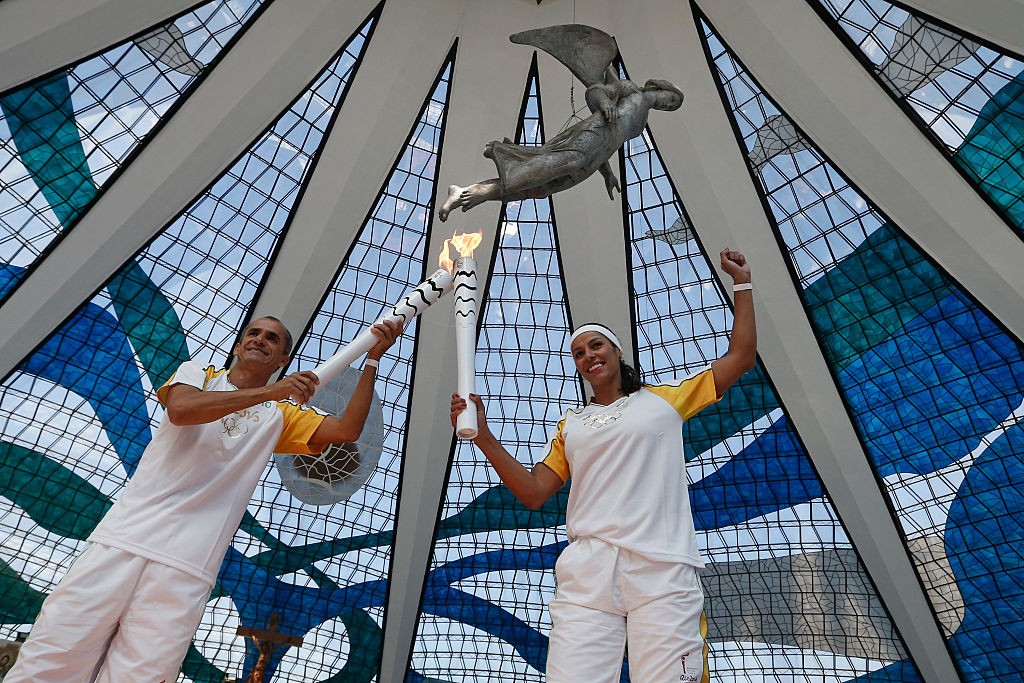 BRASILIA, DF - MAY 03: Former Marathon runner Vanderlei Cordeiro passes the Olympic Torch to Paula Pequeno in Cathedral of Brasilia during the Olympic Flame torch relay on May 3, 2016 in Brasilia, Brazil. The Olympic torch will pass through 329 cities from all states from the north to the south of Brazil, until arriving in Rio de Janeiro on August 5, to lit the cauldron. (Photo by Handout/Getty Images)