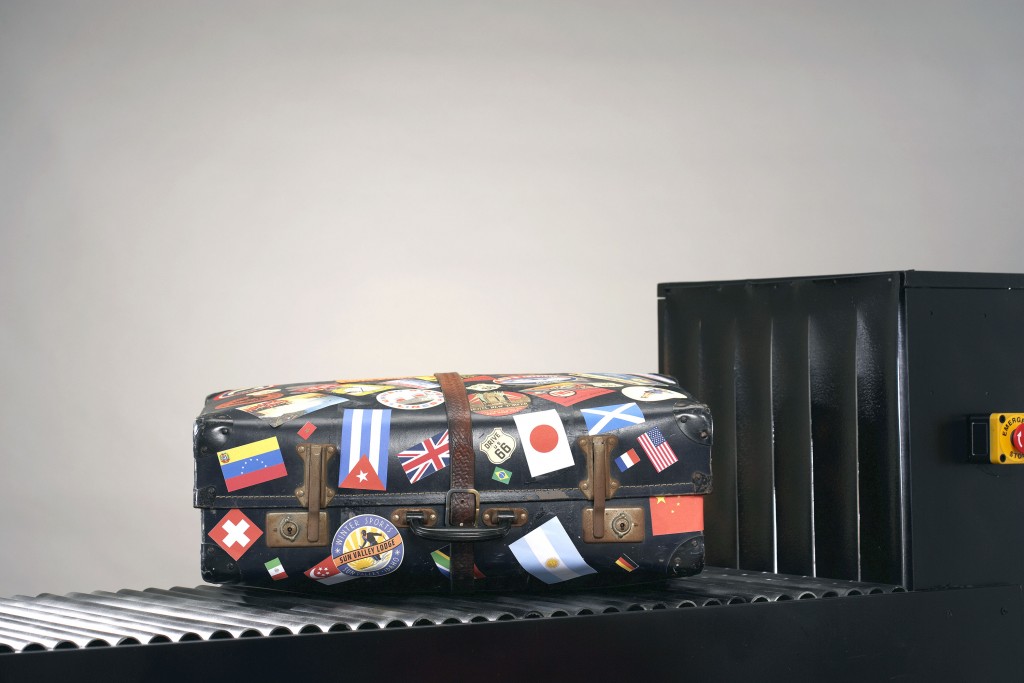 Suitcase with stickers of national flags on conveyor belt