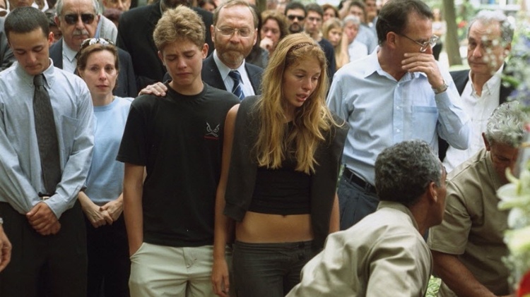 Na imagem, Andreas Von Richthofen, ao centro de preto, comparece ao enterro dos pais, em novembro de 2002; ele aparece ao lado da irmã, Suzane, que ainda não era considerada suspeita de envolvimento no crime; à esquerda, de gravata, está Daniel Cravinhos, namorado de Suzane e autor dos assassinatos