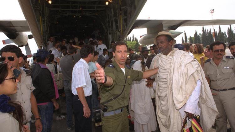 Oficial israelense auxilia judeus etíopes repatriados na Operação Salomão após saírem do avião C-130 Hercules