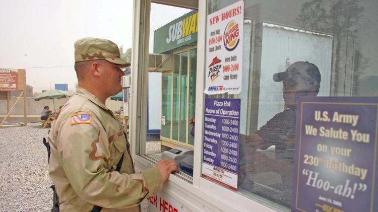 Militar faz pedido em lanchonete da Pizza Hut ao lado de outra da Subway no Campo Vitória, em Bagdá (Iraque), em plena guerra no país em 2005