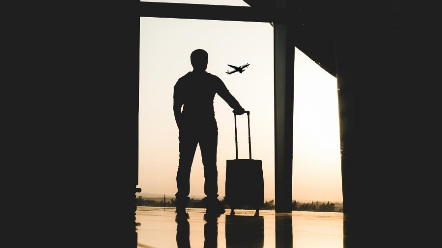 Terminal de aeroporto vazio com passageiro observando avião decolar