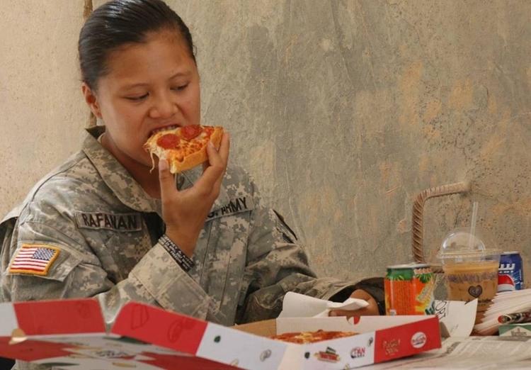 Militar dos EUA come um pedaço de pizza da lanchonete Pizza Hut na  Base Warhorse, no Iraque, em 2009