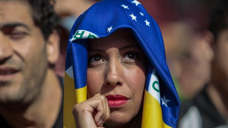 Torcedora se protege do sol com a bandeira do Brasil - AFP PHOTO / Miguel SCHINCARIOL - AFP PHOTO / Miguel SCHINCARIOL