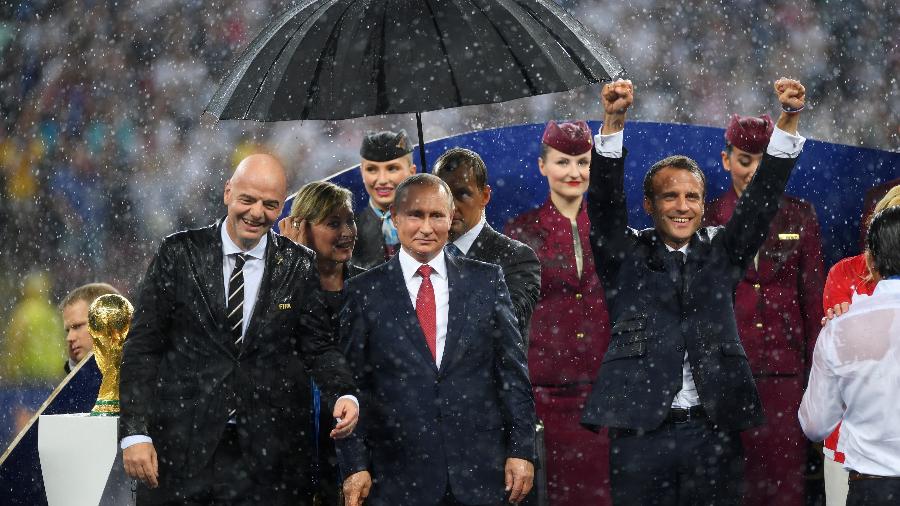 Gianni Infantino (presidente da Fifa), Vladimir Putin (presidente da Rússia) e Emmanuel Macron (presidente da França) dividem o palanque da final da Copa de 2018 sob chuva no estádio Luzhniki, em Moscou - Shaun Botterill/Getty Images
