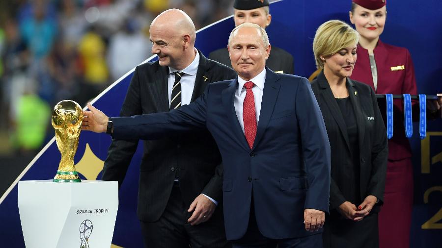 À frente de Gianni Infantino, presidente da Fifa, Vladimir Putin, presidente da Rússia, toca a taça da Copa do Mundo - Shaun Botterill/Getty Images
