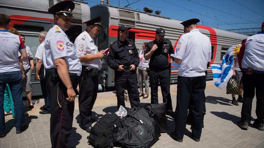 Agentes de segurança acompanham a chegada dos torcedores à estação de Volgogrado. Dois torcedores ingleses, que não aparecem nesta imagem, foram retirados de um trem que estava a caminho da estação. - AFP PHOTO / NICOLAS ASFOURI
