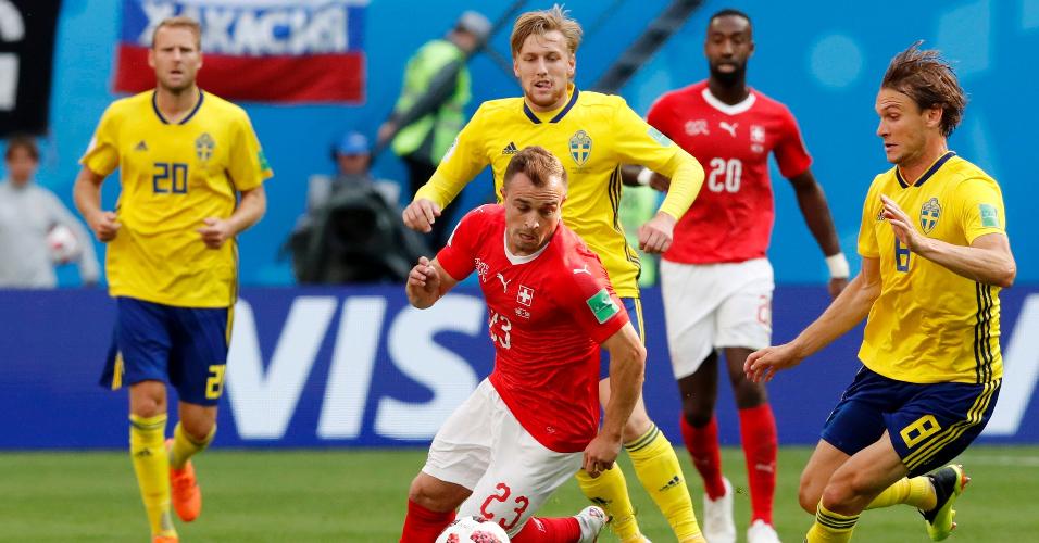 Xherdan Shaqiri, da Suíça, conduz a bola marcado por jogadores da Suécia