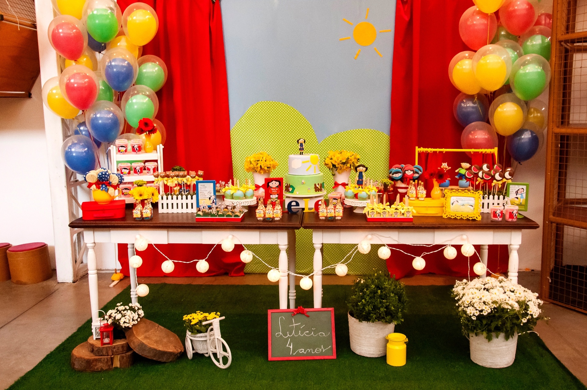 Para a parede da mesa do bolo, Rosângela Ribeiro, da Mariah Festas, confeccionou uma cortina vermelha com a paisagem que costuma aparecer no desenho quando Luna e sua turma apresentam  o que aprenderam naquele episódio. Vasos, bicicletas e peças de madeira também foram utilizadas para ambientar o jardim do desenho - George Montezani Fotografia