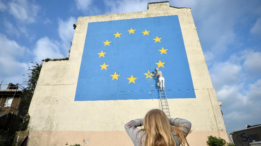 Jovem observa mural de Banksy em Dover - REUTERS/Hannah McKay