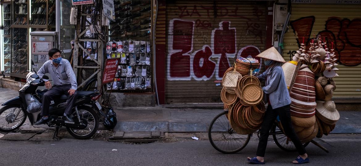 Vendedores utilizam máscaras para circularem por Hanoi, no Vietnã - Getty Images