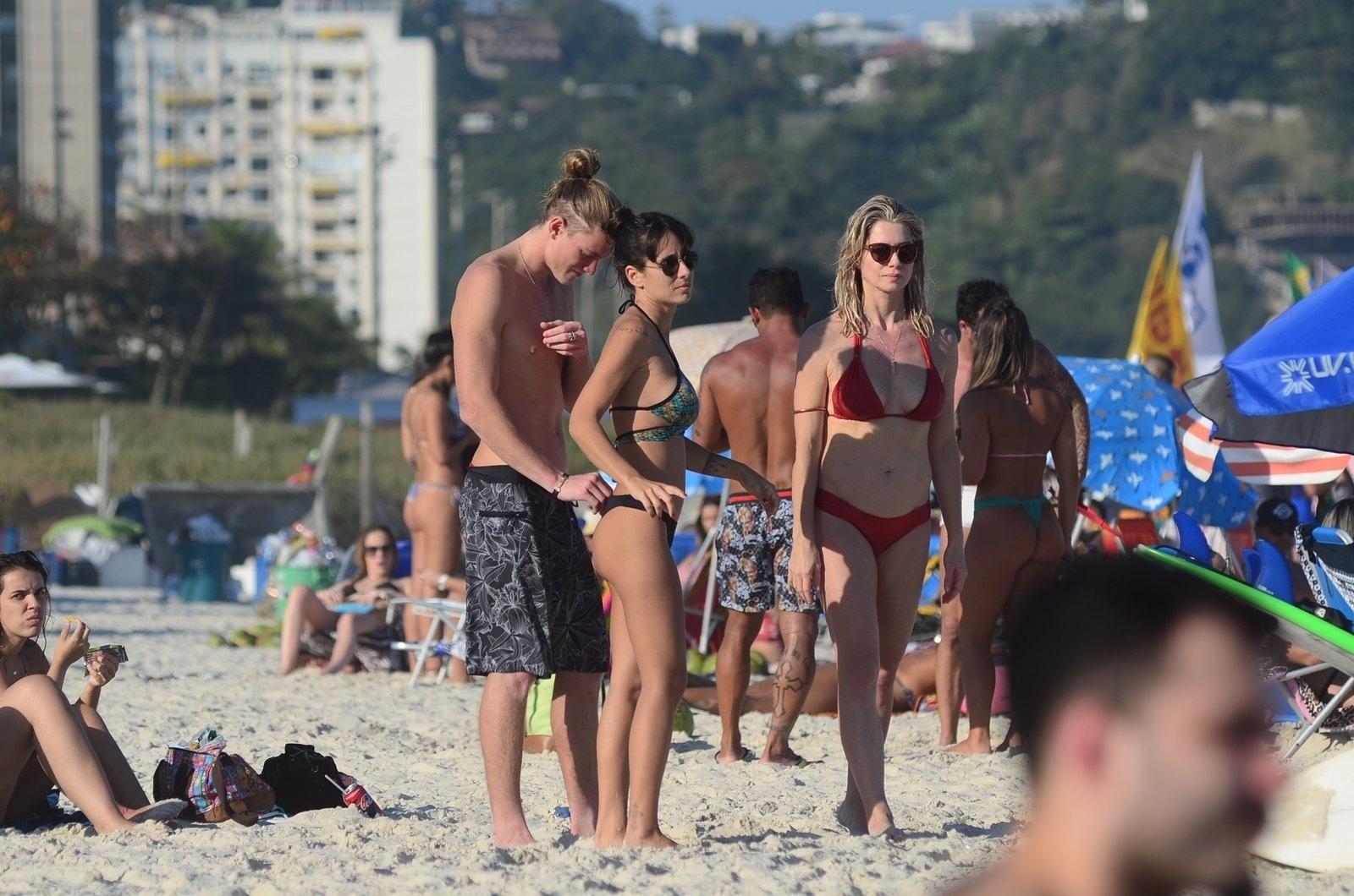 Pedro Novaes, de 21 anos, a namorada e a mãe, Letícia Spiller, de 45, curtem praia na Barra da Tijuca, zona oeste do Rio, neste domingo (8) - Webert Belicio/AgNews