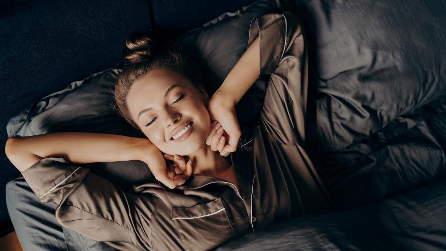 Mulher acorda feliz após boa mensagem - iStock