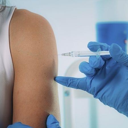 Mulher tomando vacina no braço - iStock