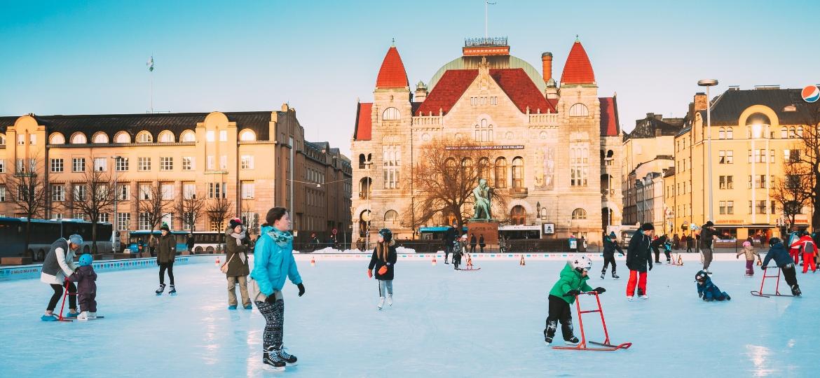 Crianças esquiam no gelo e brincam na praça em frente ao Teatro Nacional Finlandês em Helsinque - bruev/Getty Images