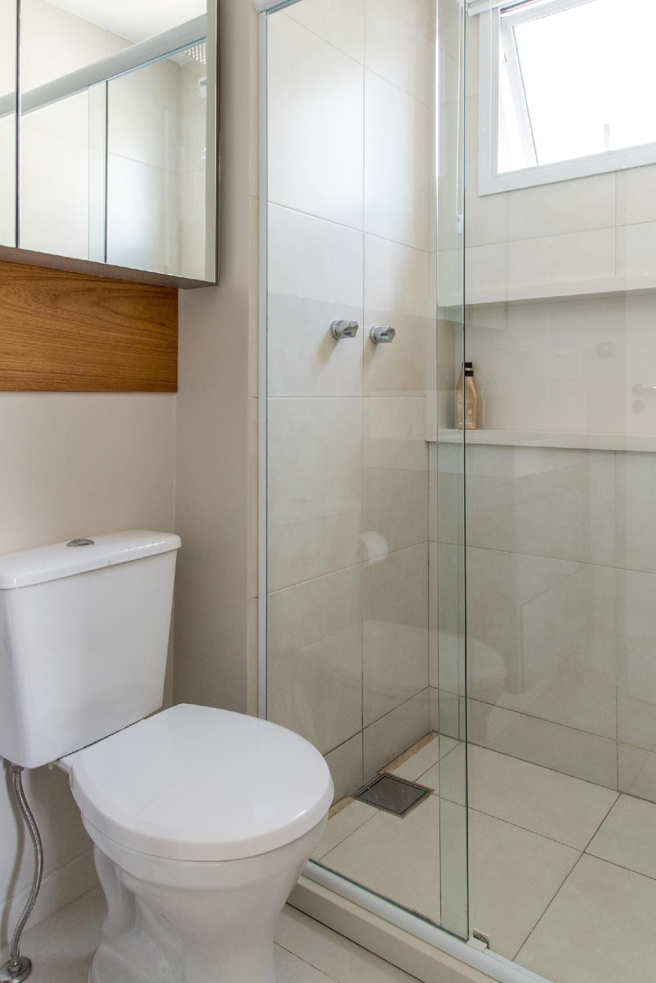 No banheiro da Spaço Interior, o armário superior segue até o teto para aproveitar melhor a área. Com pouca espessura, ele é perfeito para organizar acessórios menores. As arquitetas também optaram por um vaso sanitário mais compacto. Imagem: Julia Herman | Divulgação - Julia Herman | Divulgação