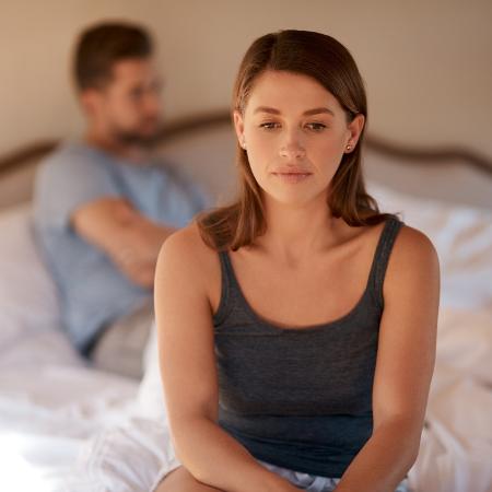 Shot of a young woman sitting on the edge of the bed after arguing with her husband; mulher na cama; sem sexo; casal em crise; discussão - PeopleImages/Getty Images