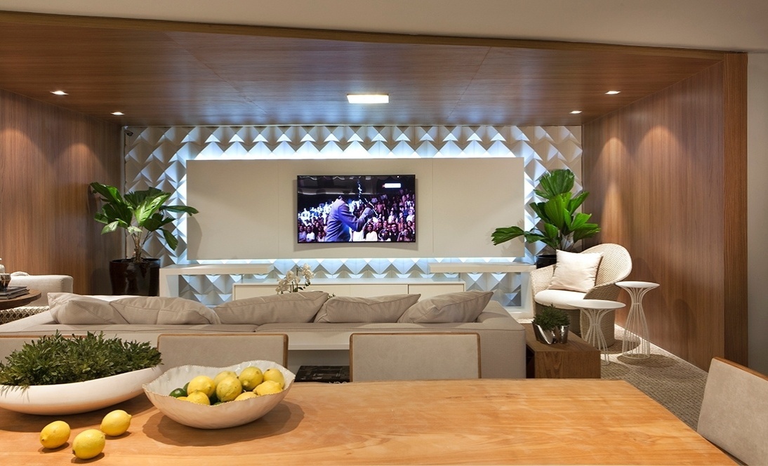 Na sala, homogeneizando as superfícies - Tem ambientes sociais integrados em casa? Uma alternativa é demarcar um dos cômodos utilizando a madeira, como fez Isabele Melo no Refúgio do Jovem. Aberto em relação à sala de jantar, o estar ganhou superfícies amadeiradas - que parecem encaixotar o espaço, deixando-o homogêneo - combinadas a um acabamento branco volumétrico (ao fundo) | A Casa Cor Espírito Santo (www.casacor.com.br) fica em cartaz até 10 de novembro de 2015 - Felipe Araújo/ Divulgação