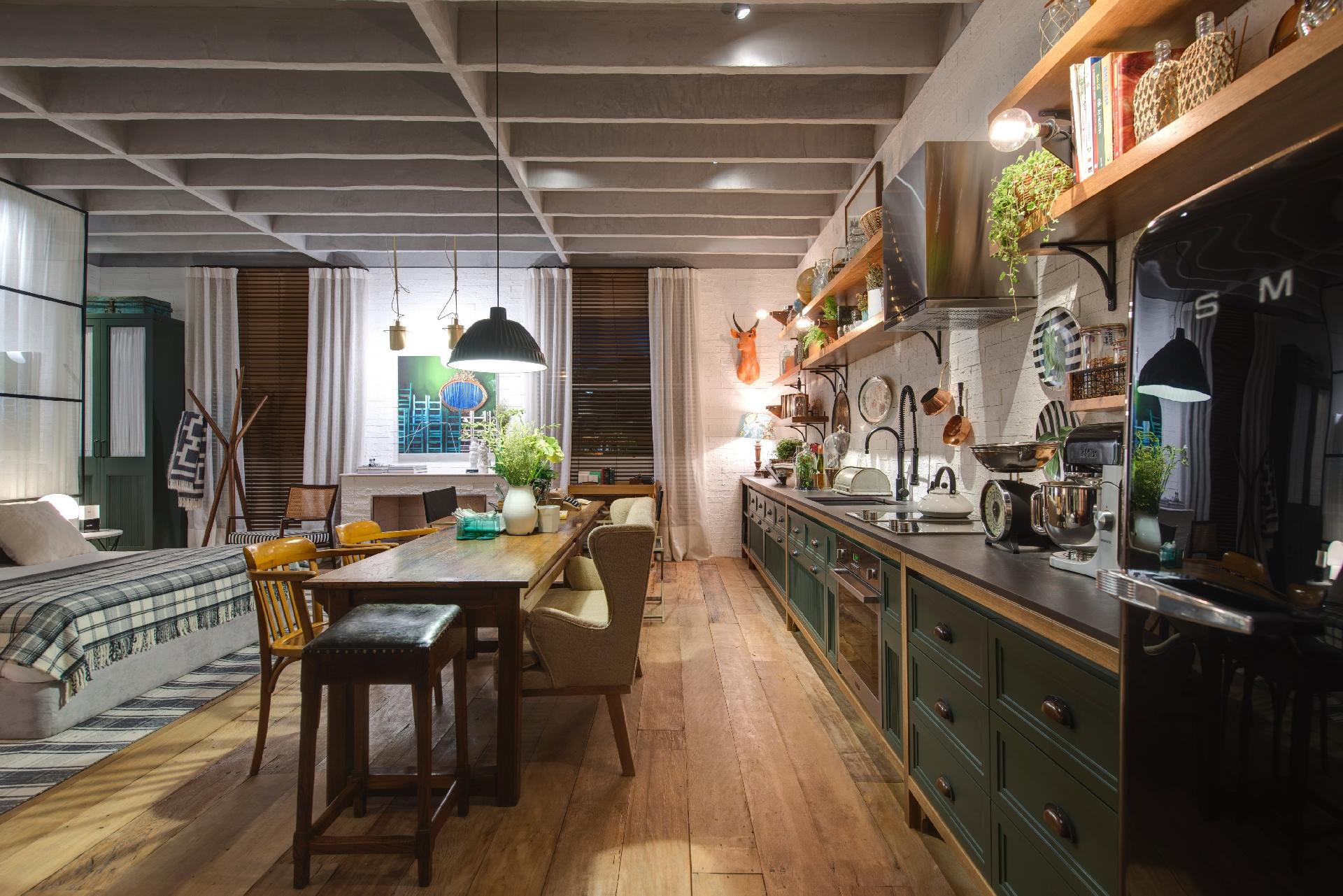 A mesa disposta no meio do loft é dividida em dois: a primeira parte serve para as refeições e conta com um sofá de espaldar alto no lugar de duas cadeiras. A segunda parte é usada como escrivaninha. No Loft do Campo, assinado por Paola Ribeiro para a Casa Cor SP, o piso é de madeira de demolição - Katia Kuwabara/UOL