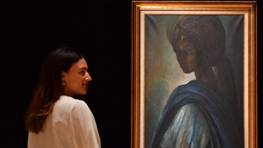 Mulher observa o quadro "Tutu", de Ben Enwonwu, que é chamado de "Mona Lisa africana" - AFP