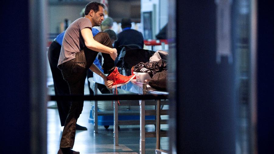 Homem tirando os sapatos para passar pela segurança do Aeroporto John F. Kennedy em Nova York, nos EUA, em 2012 Homem tirando os sapatos para passar pela segurança do Aeroporto John F. Kennedy em Nova York, nos EUA, em 2012