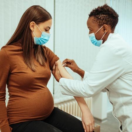 Mulher grávida toma vacina - iStock