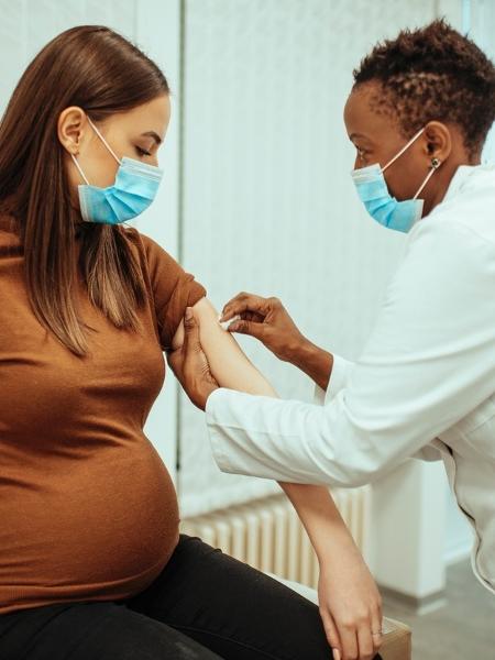 Mulher grávida tomando vacina - iStock