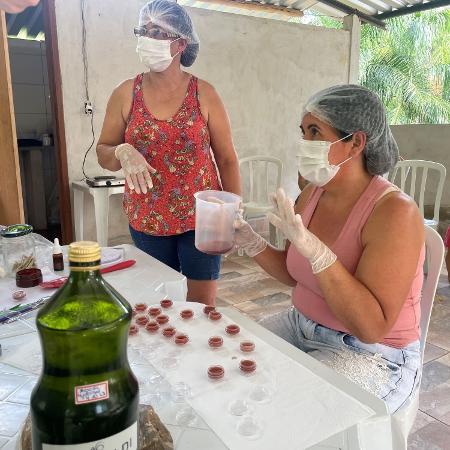 Duas mulheres aprendem a fazer bálsamo labial natural com óleo essencial extraído das folhas de aroeira. Os produtos podem eventualmente ser vendidos, ajudando a gerar renda adicional e aumentar o valor da floresta em pé