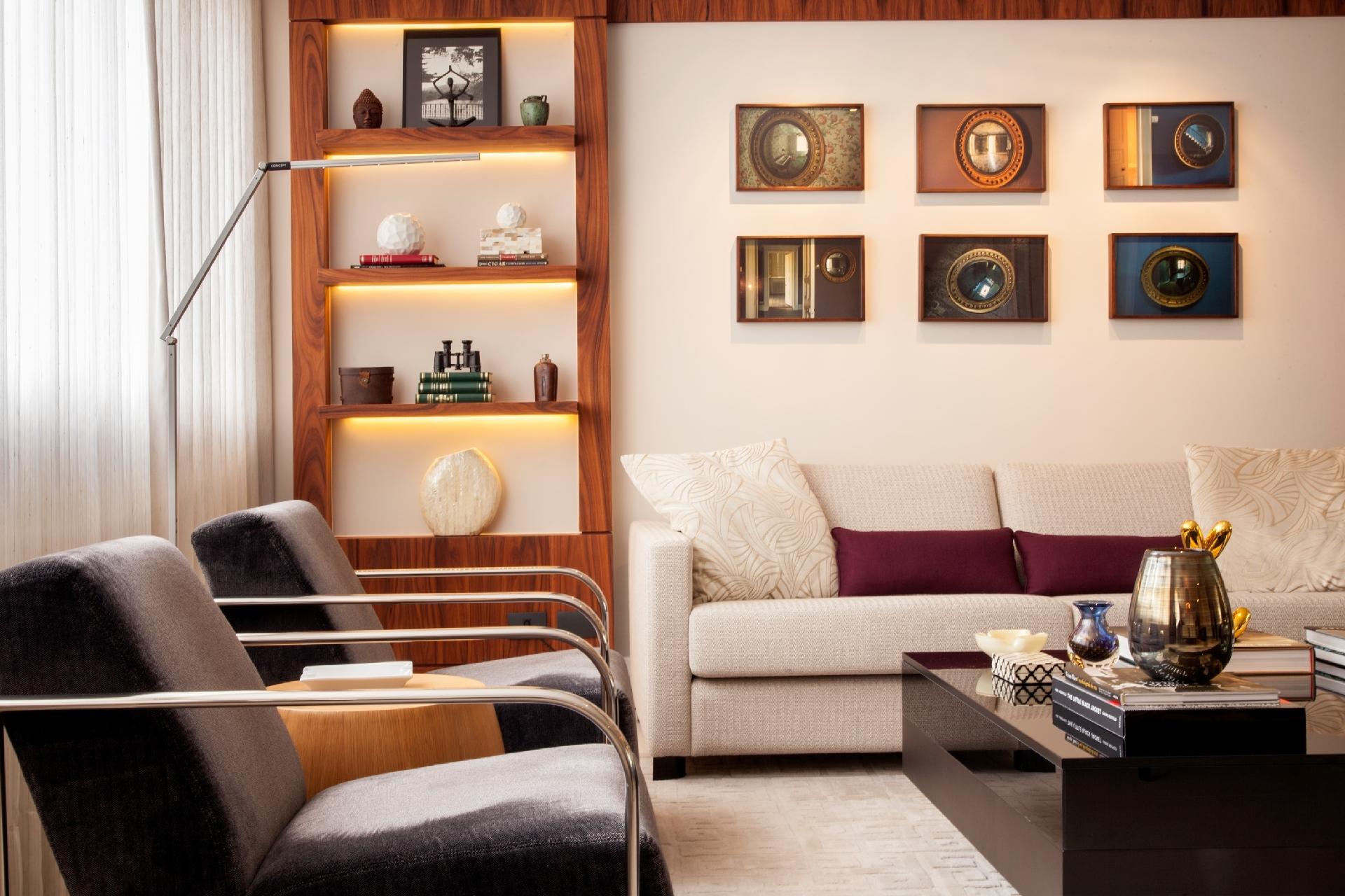 Inserido na reforma de Leonardo Junqueira, o painel de madeira evidencia com estilo e charme a coleção de objetos e obras de arte dos moradores. Para valorizá-los ainda mais, o arquiteto projetou pequenos rasgos no móvel para embutir as fitas de led. Luminárias de piso auxiliam a leitura - J. Vilhora/Divulgação