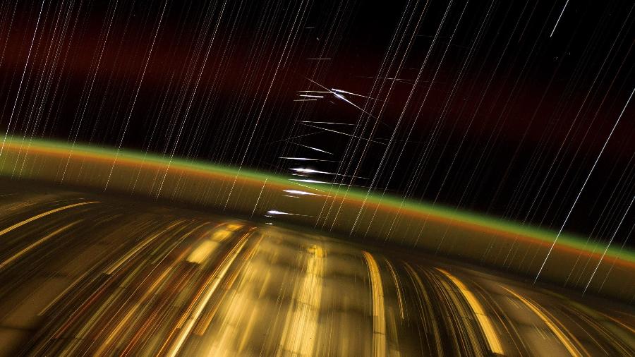 Capturada pelo astronauta Don Pettit, foto de longa exposição exibe as luzes das cidades da Terra, o brilho da alta atmosfera e estrelas em rastros. Os flashes brilhantes no centro são reflexos da luz solar nos satélites Starlink da SpaceX em órbita baixa da Terra. Capturada pelo astronauta Don Pettit, foto de longa exposição exibe as luzes das cidades da Terra, o brilho da alta atmosfera e estrelas em rastros. Os flashes brilhantes no centro são reflexos da luz solar nos satélites Starlink da SpaceX em órbita baixa da Terra.