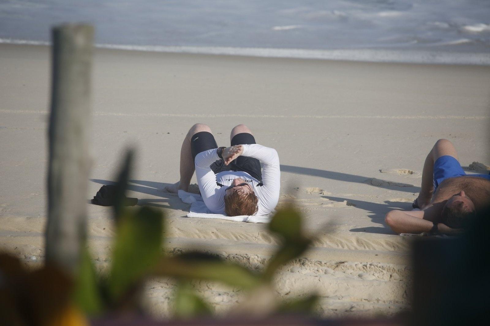 De bermuda e camisa, Ed Sheeran relaxa na areia da praia de Grumari, na zona oeste do Rio - Ag.News